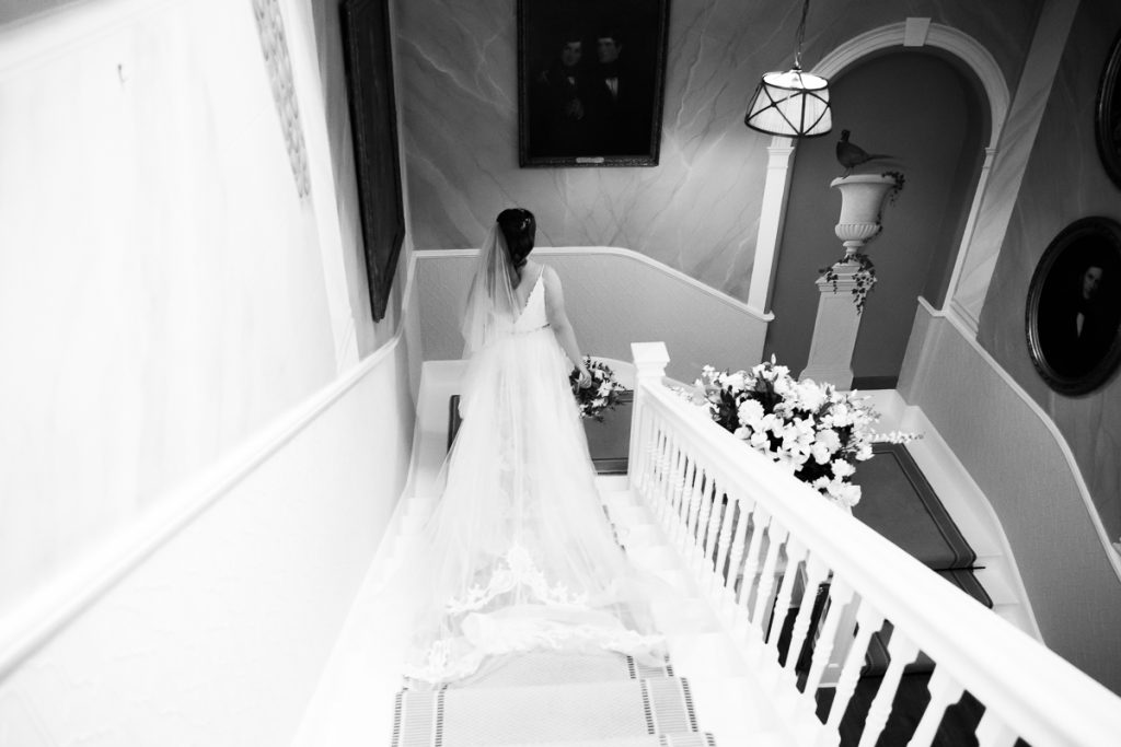 wedding photography at hodsock priory.Bride walking down the stairs in black and white.