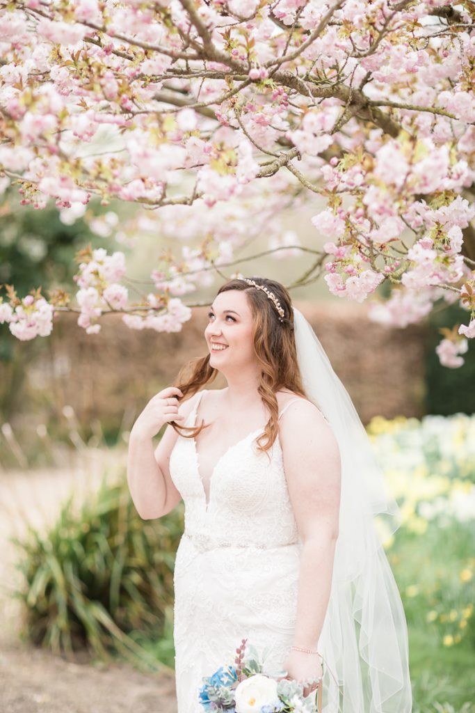 wedding photography at hodsock priory. The bride on her own with the cherry blossom.
